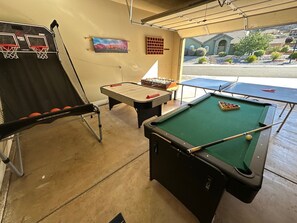 A recreational area with a pool table, foosball table, and a basketball hoop.