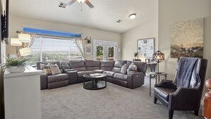 A living room with a sectional sofa, a round coffee table, a decorative chair, and a ceiling fan. - Perfect location close to Zion! (La Verkin)