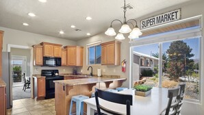 A kitchen with wooden cabinets, a black stove, and a large island with stools. - Perfect location close to Zion! (La Verkin)