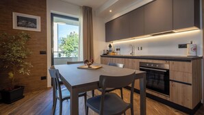 A modern kitchen with wooden cabinets, a built-in oven, and a dining area with a table and chairs.
