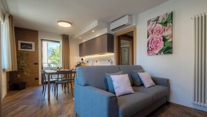 A modern living room with a grey sofa, a dining table, and a kitchen area.