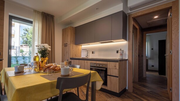A modern kitchen with wooden cabinets, a dining table set with breakfast items, and a view of the outdoors.