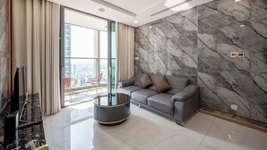 Un salon moderne avec un canapé gris, une table basse ronde et une grande fenêtre avec des rideaux.