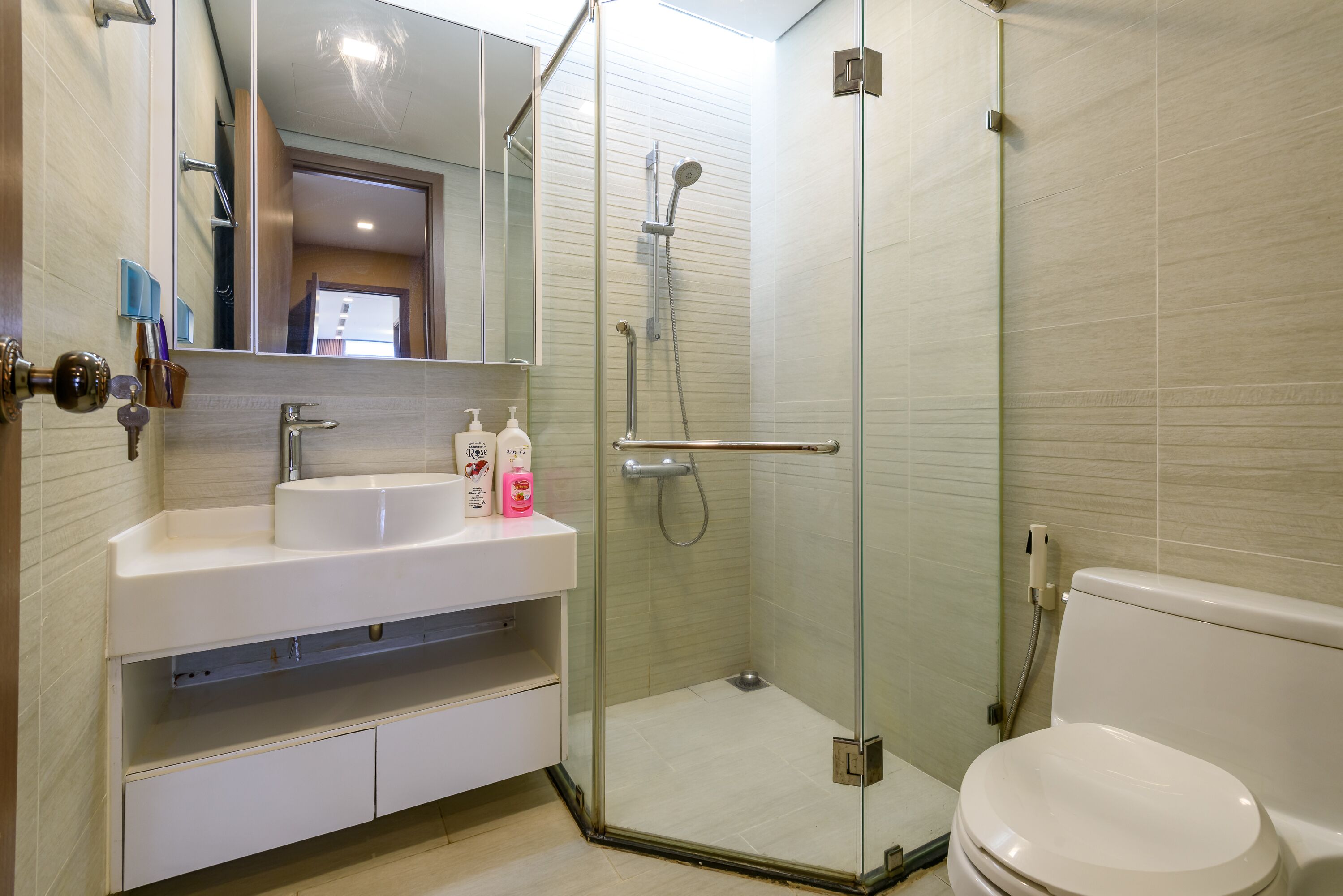 A modern bathroom with a glass-enclosed shower, a white sink, and a toilet.