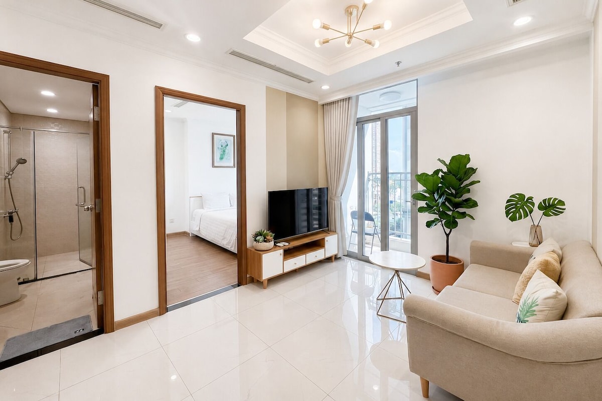 A modern living room with a sofa, a TV, a balcony with a view, and a shower area.