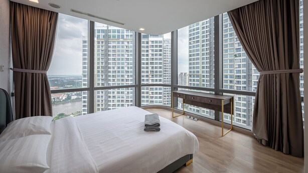Une chambre d’hôtel moderne, dotée d’un grand lit, d’un bureau et offrant une vue sur les gratte-ciel.