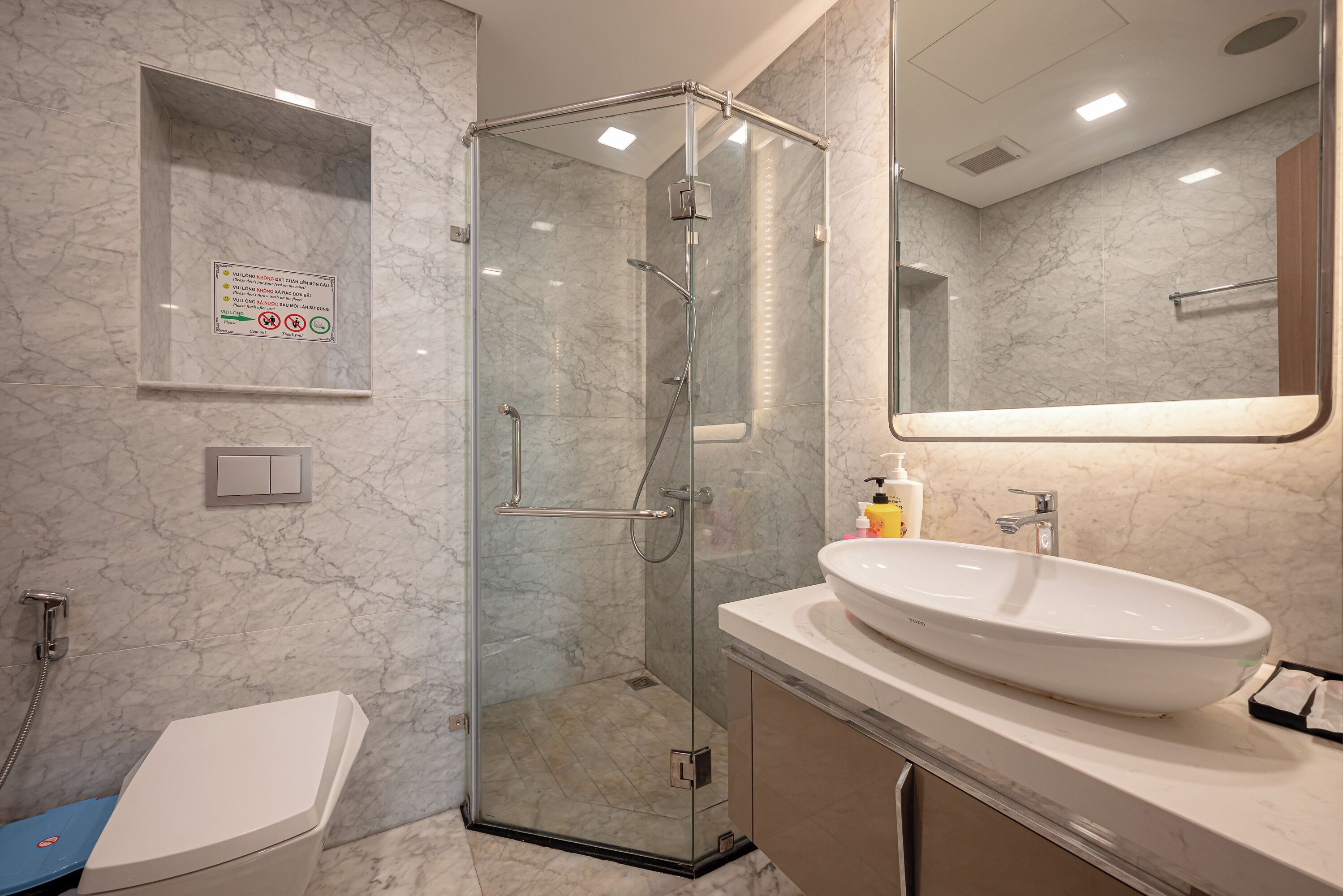 A modern bathroom with a glass-enclosed shower, a white sink, and a mirror above the sink.