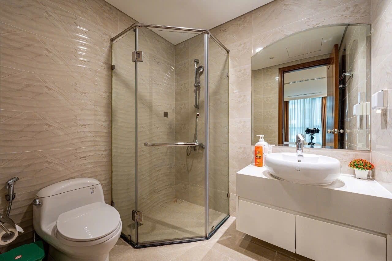 A modern bathroom with a glass-enclosed shower, a white sink, and a toilet.