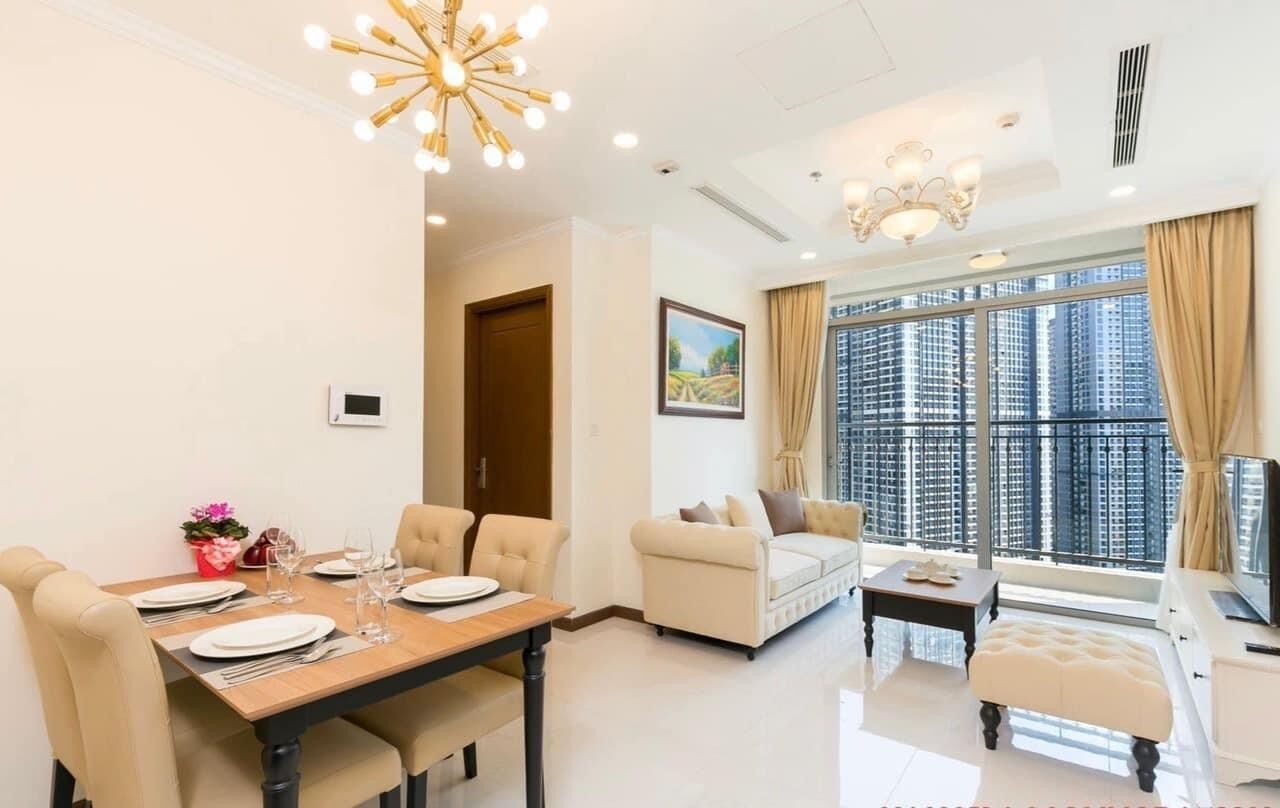 A modern living room with a dining area, large windows, and a view of high-rise buildings.
