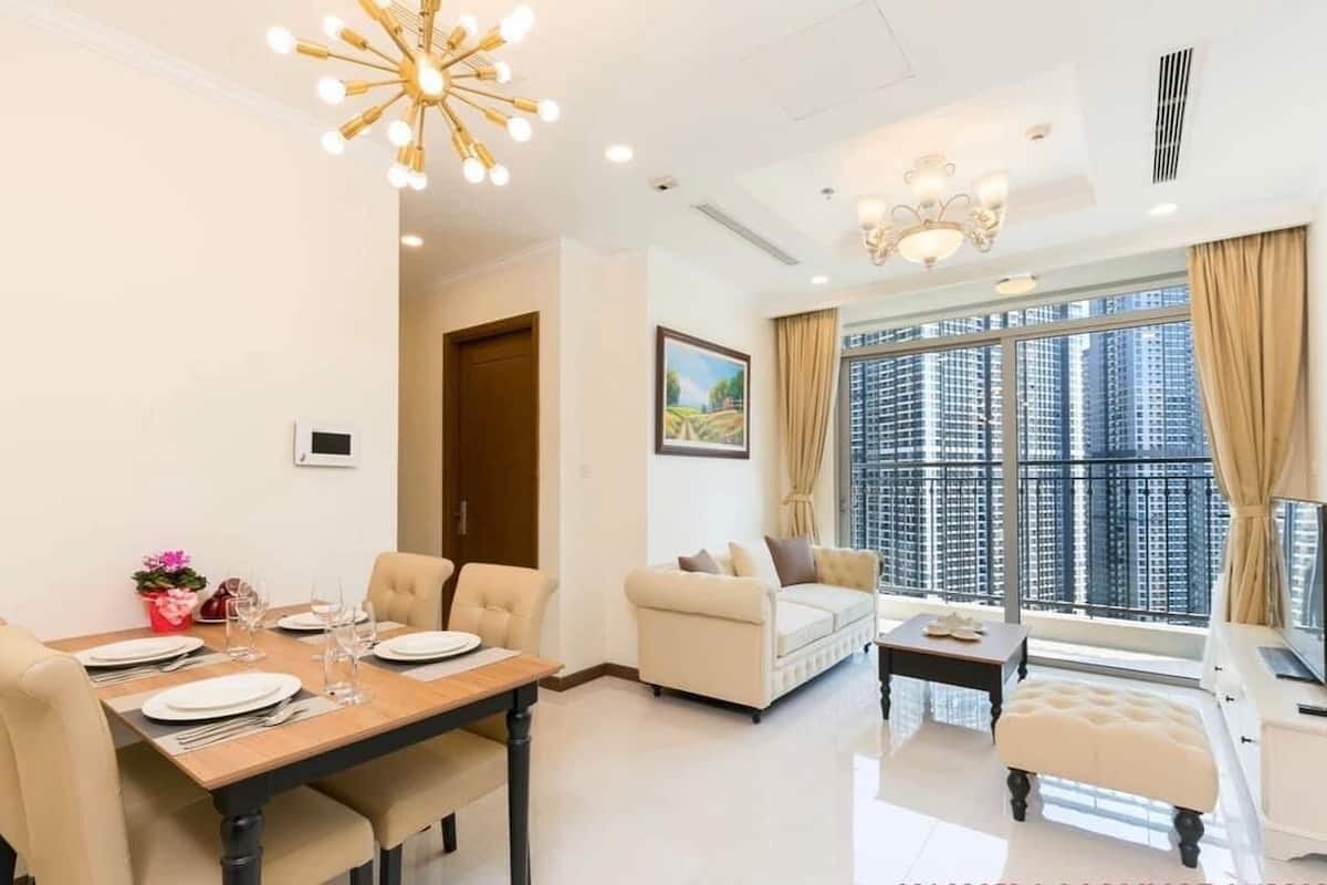 Una sala de estar moderna con comedor, ventanas amplias y vistas a edificios altos.