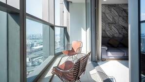 Un balcon moderne avec vue sur la ville, un canapé et deux fauteuils.