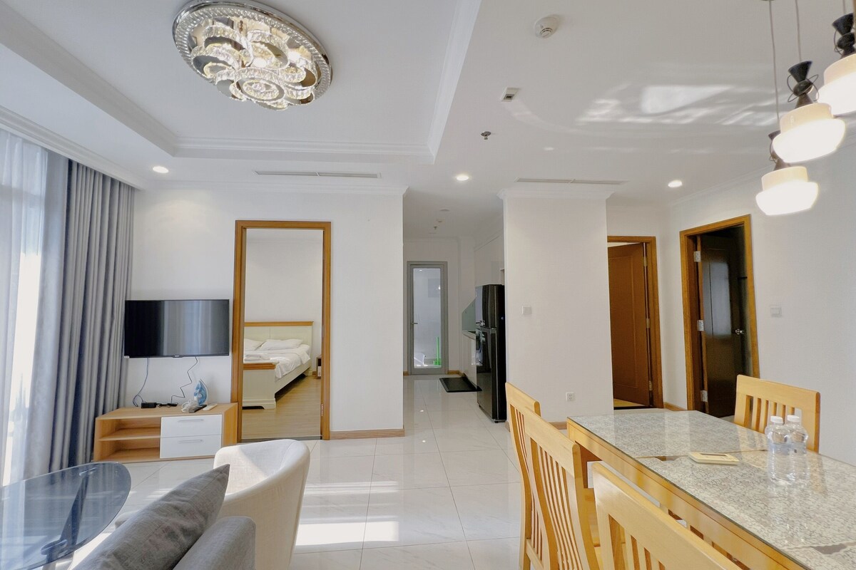 Una habitación de hotel moderna con una cama, televisión, zona de comedor con mesa y sillas, y una cocina.