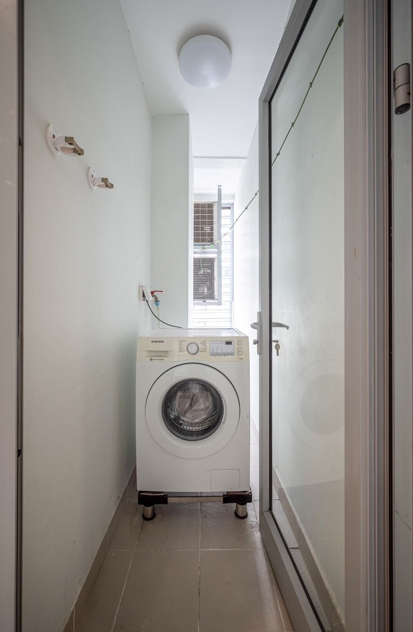 Een smalle gang met een wasmachine links en een schuifdeur naar het glas rechts.