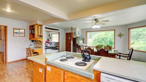 A spacious kitchen with wooden cabinets, a central island, and a dishwasher. - Cozy Washington Retreat w/ Deck, Walk to Beach! (Pacific Beach)