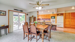 A dining area with a wooden table and chairs, a ceiling fan, and a kitchen with wooden cabinets and appliances. - Cozy Washington Retreat w/ Deck, Walk to Beach! (Pacific Beach)