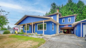 A two-story house with a blue exterior, a front porch, and a garage. - Cozy Washington Retreat w/ Deck, Walk to Beach! (Pacific Beach)