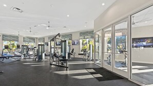 Uma academia moderna com esteiras, máquinas de musculação e uma grande janela com vista para o exterior.