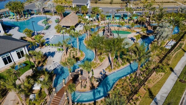 Vista aérea de um resort com várias piscinas, palmeiras e um tobogã sinuoso.