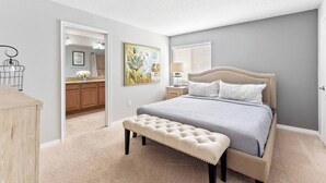 Quarto com cama, um banco e vista para o banheiro.