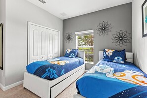A bedroom with two beds, a window, and decorative wall art.