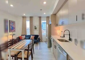 Un appartement moderne comprenant un coin repas, un canapé, une cuisine avec un évier et une vue par la fenêtre.