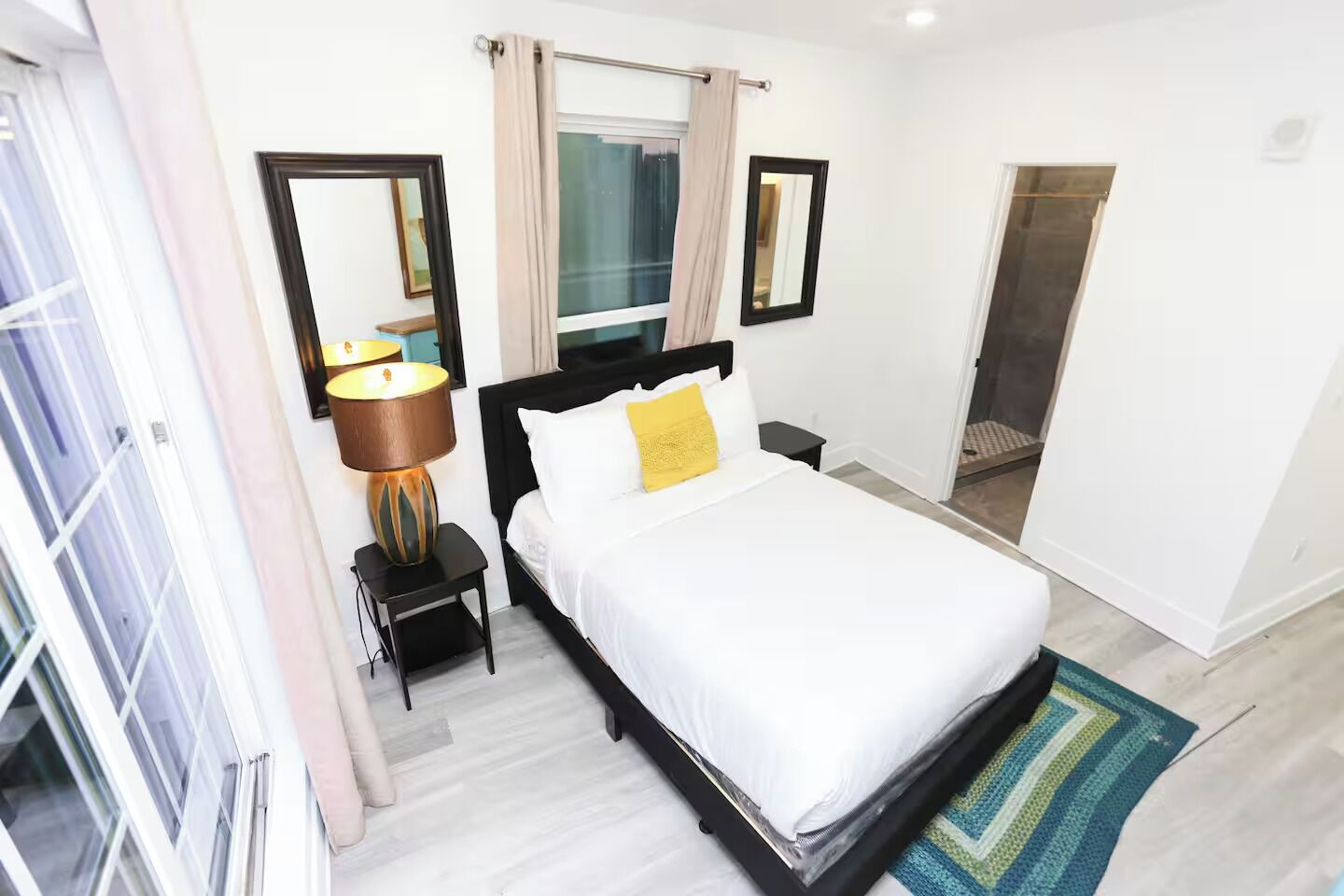 A hotel room with a bed, bedside table, lamp, and a mirror.
