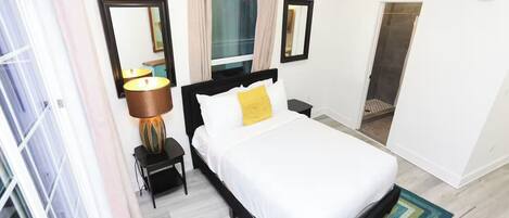 A hotel room with a bed, bedside table, lamp, and a mirror.