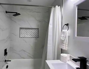 Une salle de bain moderne équipée d’une douche, de toilettes et d’un lavabo.