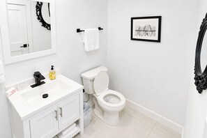 A bathroom with a white sink, toilet, and a framed picture on the wall. - Capitol Hill Stay with Stunning Skyline View (Washington)