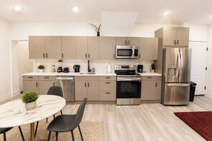 Una cocina moderna con electrodomésticos de acero inoxidable, encimera de mármol y comedor con mesa y sillas.