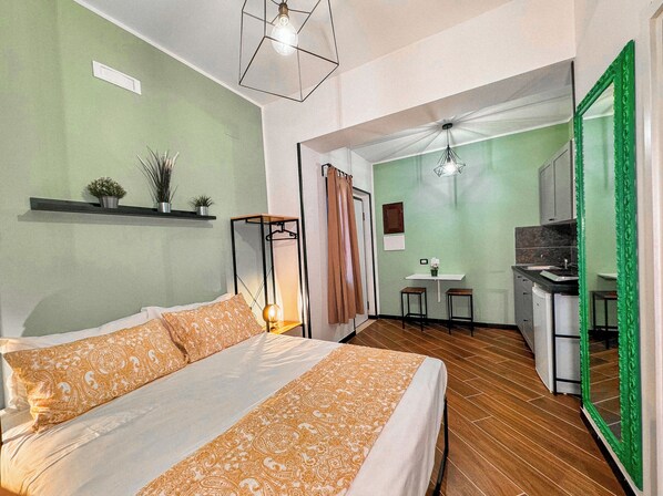 A bedroom with a bed, bedside table, and a hanging light fixture.