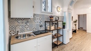 A modern kitchen with a stainless steel sink, a wooden countertop, and a patterned backsplash. - The Quarters Naples Apartment (Naples)