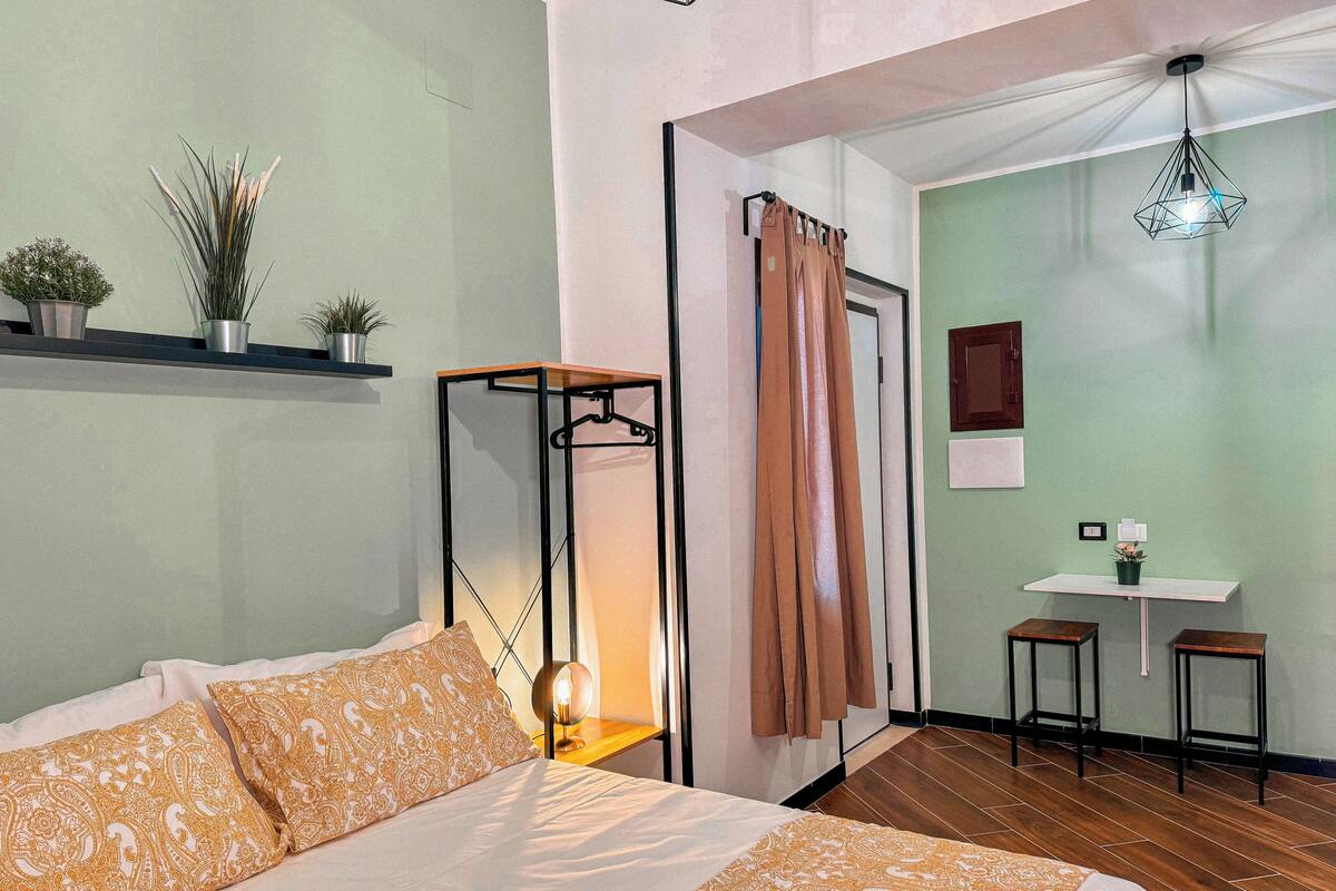 A neatly arranged bedroom with a bed, bedside table, and a hanging light fixture.
