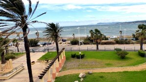 A coastal view with a paved walkway, palm trees, and a parking area. - Comfortable apartment  with pool facing the sea (Six-Fours-les-Plages)