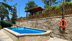 A swimming pool with a stone wall and a wooden fence in the background. - Quinta com Piscina Rodeada da Belíssima Paisagem do Alto Minho (Ponte de Lima)