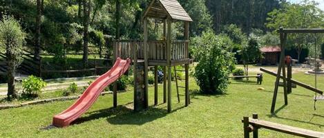 Un parque infantil con tobogán, estructura para escalar y columpios.