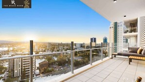 Ein Balkon eines Hochhauses mit Blick auf die Stadt, ein Essbereich mit Tisch für zwei Personen und eine Flasche Champagner.