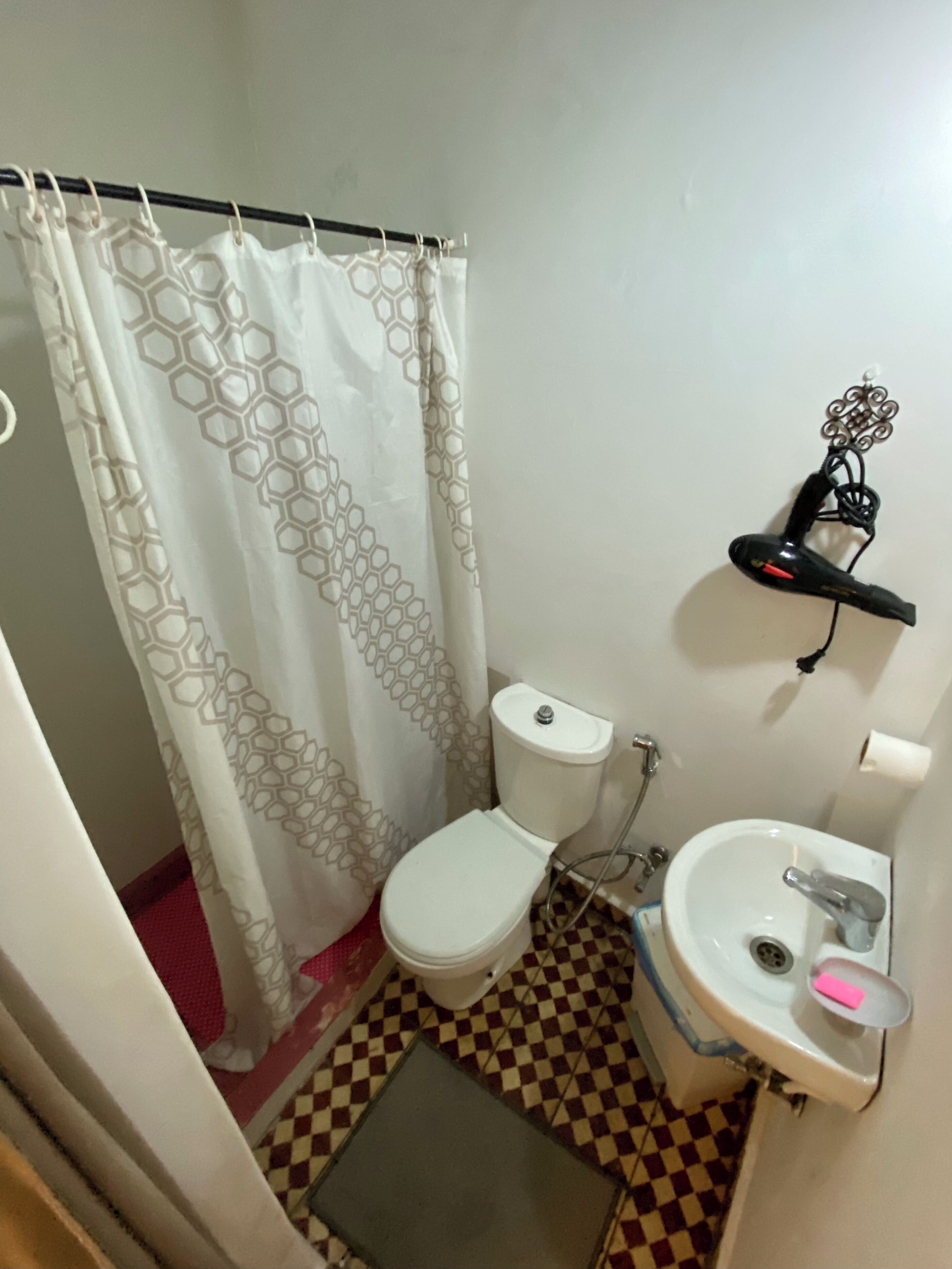 A small bathroom with a toilet, sink, and shower curtain.