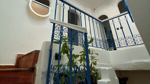 Una escalera con barandales azules, un tragaluz y plantas en macetas.