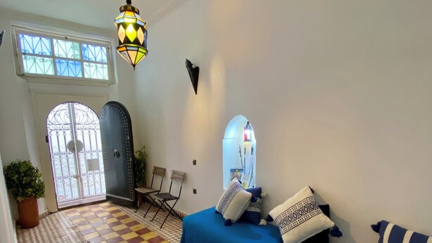 Una sala de estar con un sofá azul, alfombra estampada y un farol decorativo.