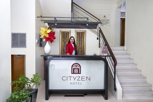 A reception desk at CityZen Hotel with a staircase and framed artwork on the wall. - Hotel Cityzen Guayaquil (Guayaquil)