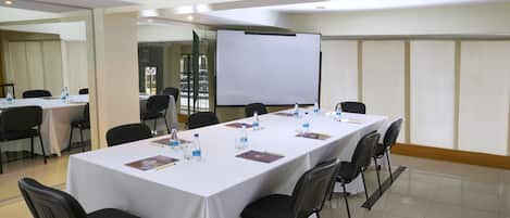 A conference room with a long table, chairs, a whiteboard, and water bottles.