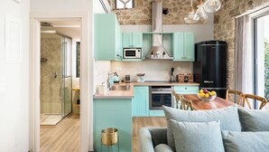 Een moderne keuken met blauwgroene kastjes, een zwarte koelkast, en een eethoek met een houten tafel en stoelen.