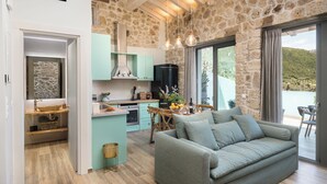 Een moderne keuken met een stenen muur, een eethoek met een tafel en stoelen, en een woonkamer met een bank.
