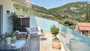 Een balkon met een bank, stoelen, een tafel en potplanten.