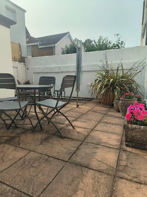Enjoy dining or socializing in this outdoor patio area with a table and four chairs.