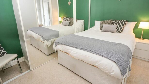 A bedroom with a bed, a chair, a nightstand, and a mirror. - Stunning 1-bed Apartment in Southsea (Portsmouth)