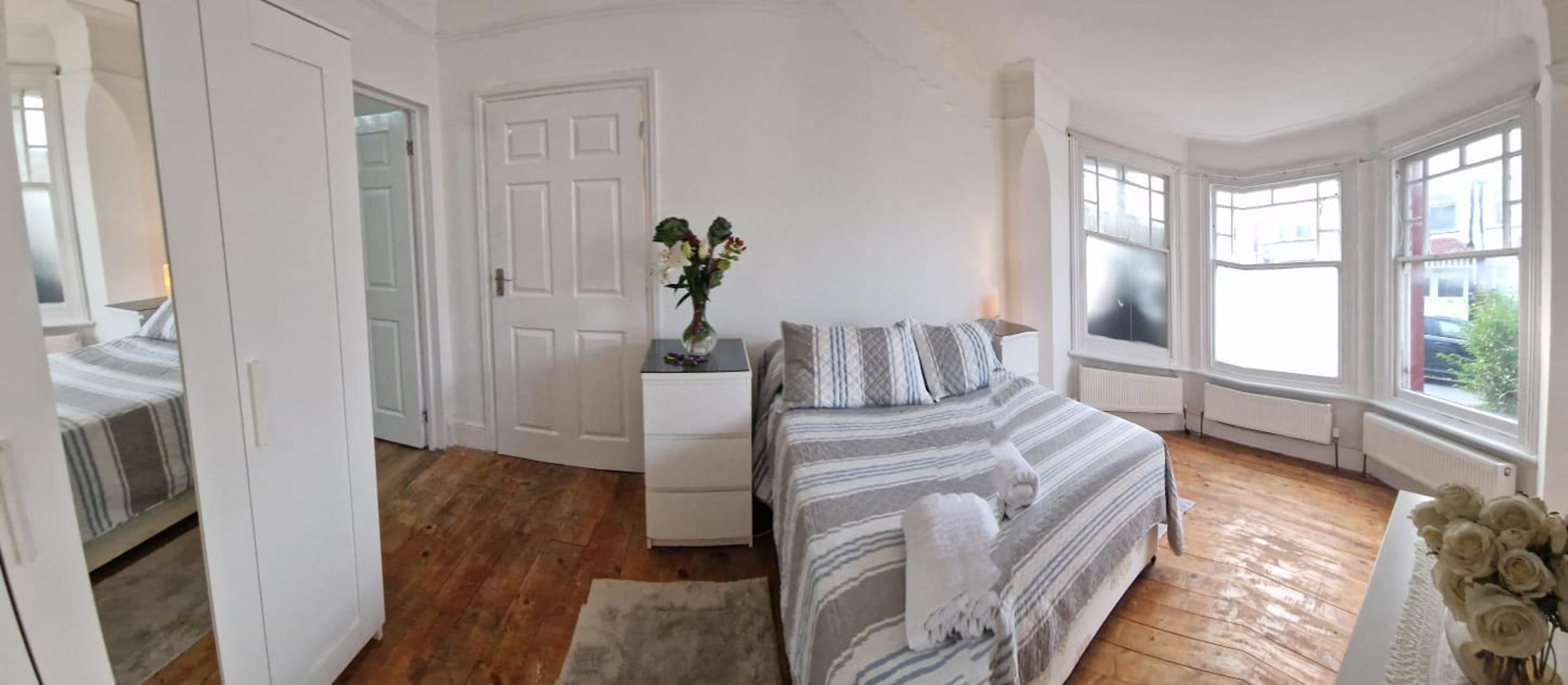 Um quarto com uma cama, cômoda, espelho e janela.