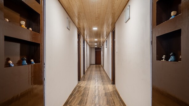 Un largo pasillo con pisos y paredes de madera, flanqueado por estantes con figuritas.