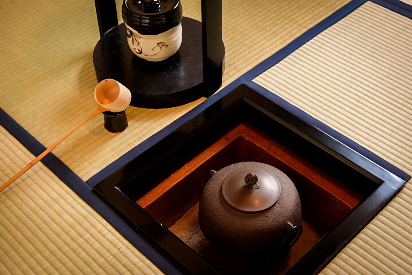 A traditional Japanese tea set on a tatami mat with a black tray and a teapot.